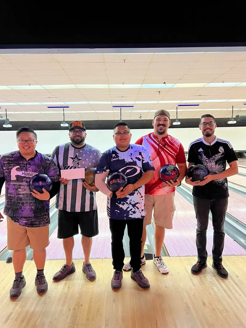 Winners of the first VangBros tournament holding their bowling balls and a prize cheque